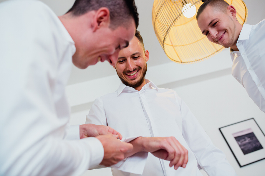 Des invités aide la mariée avec ses boutons de manchette