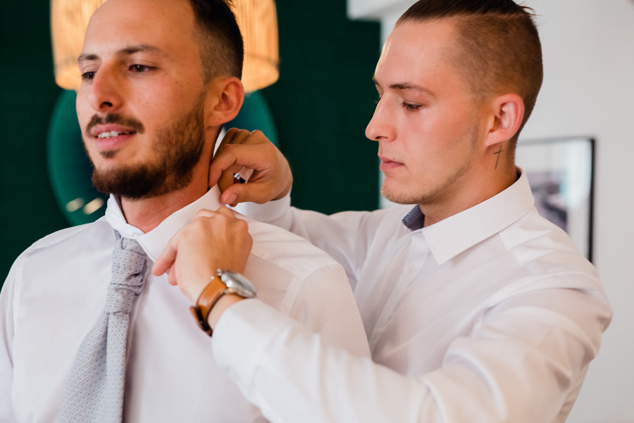 Un invité ajuste le col de la chemise du marié