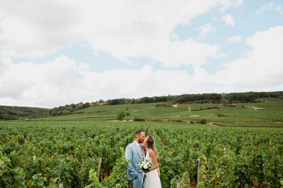 Les mariés s'embrassent au milieu des vignes