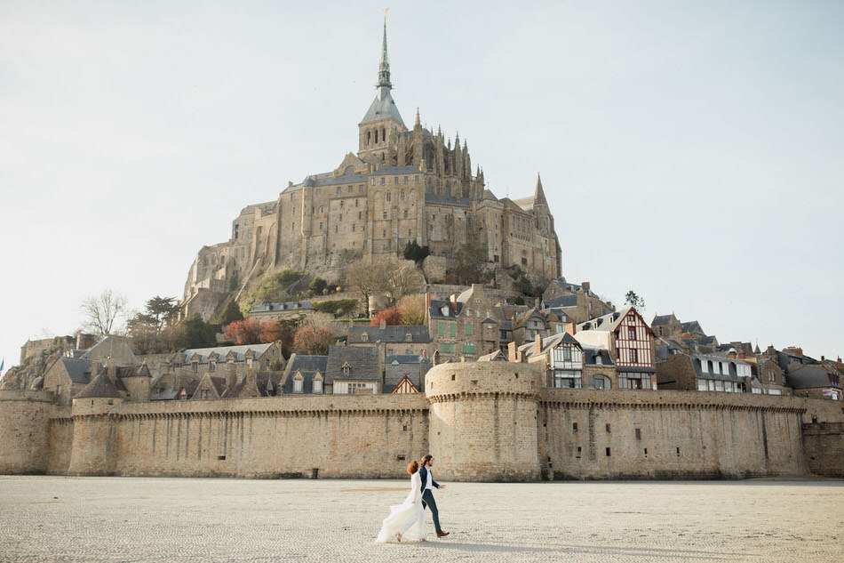 Les mariés marchent devant le mont saint michel
