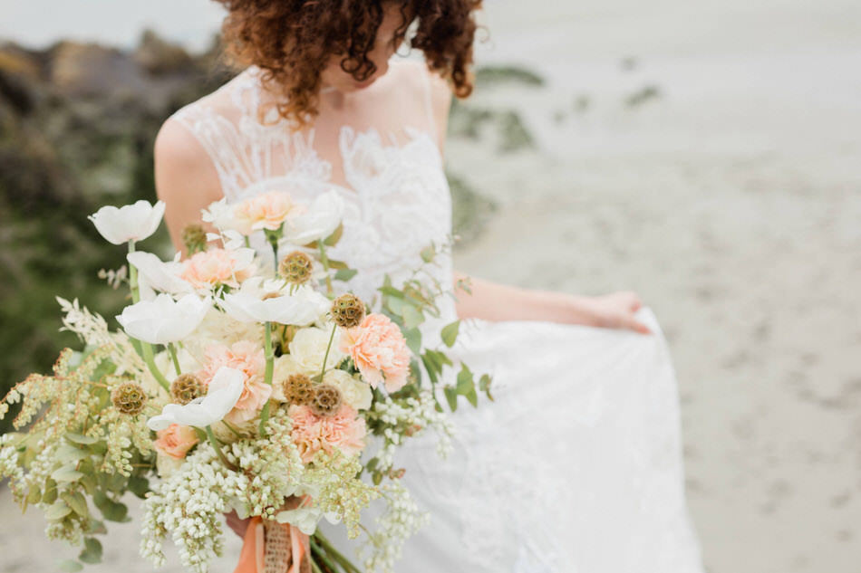 La mariée se déplace avec son bouquet sur la plage