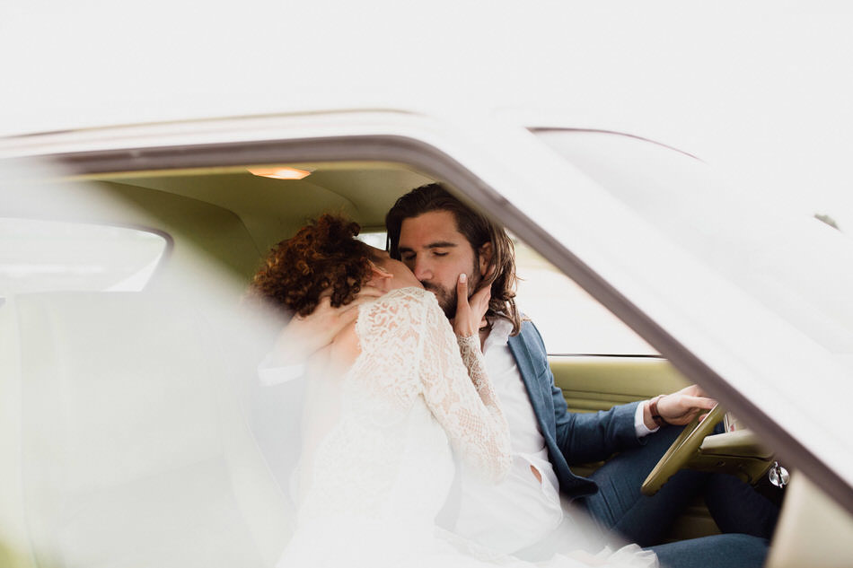 les mariés s'embrassent dans la voiture