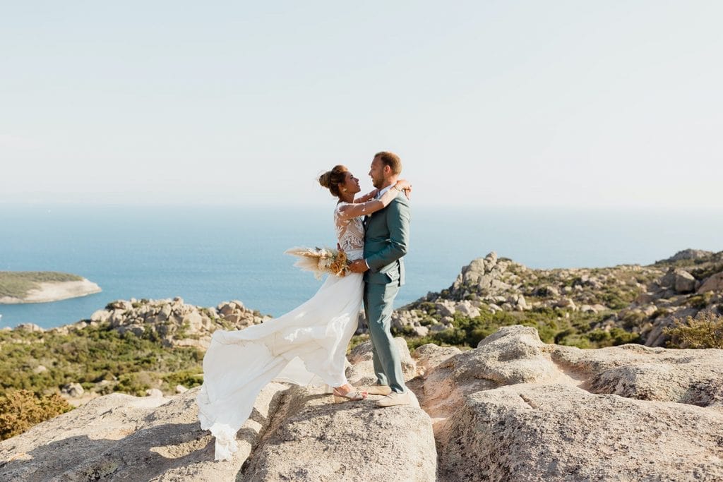 the bride and groom on the top of a corsica rock
