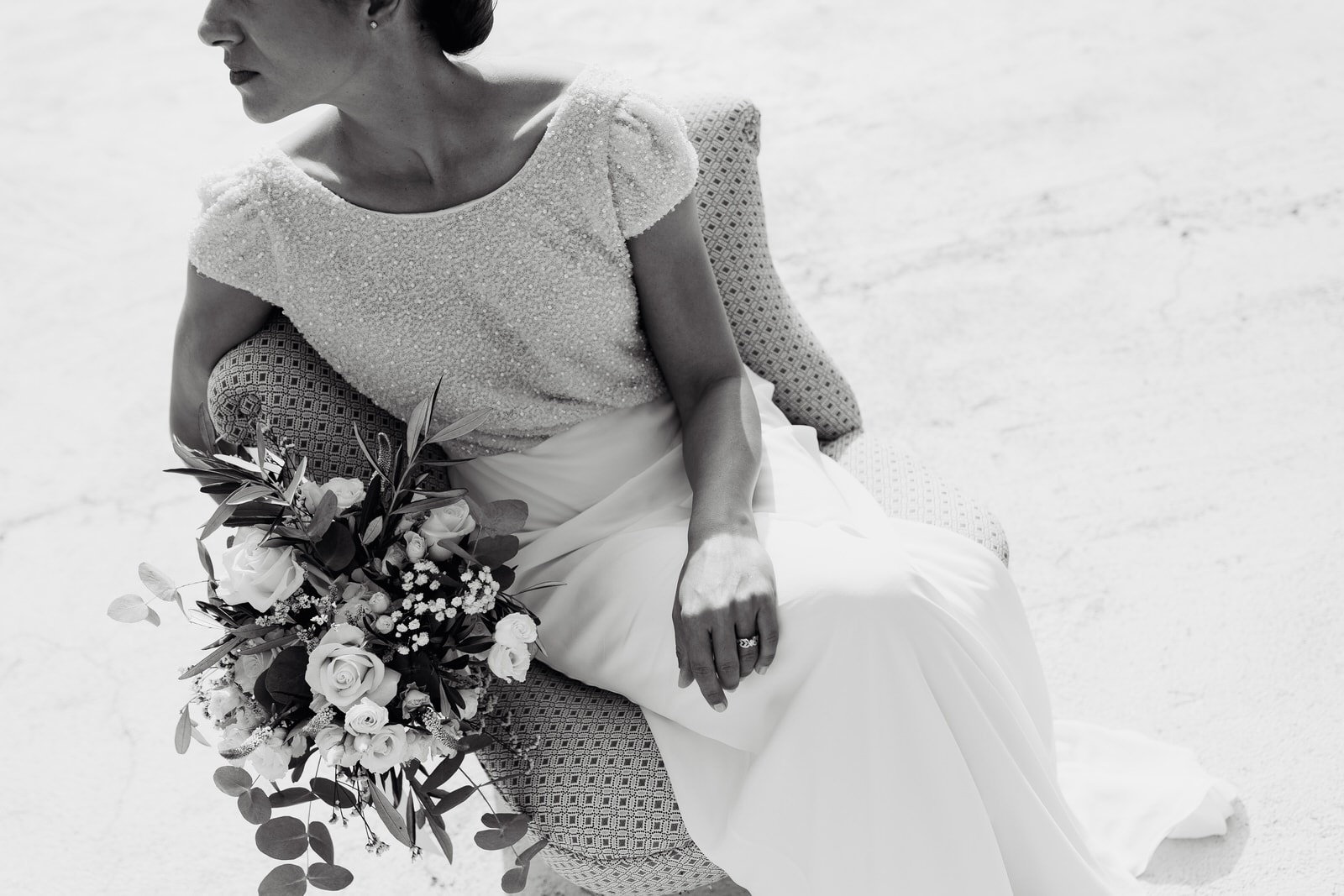 la mariée assise dans un fauteuil avec son bouquet