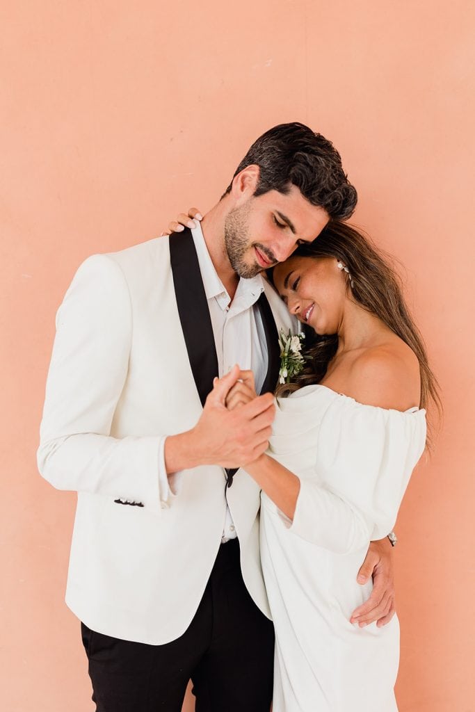 Romantic dance at Château Beauregard – Maxime Bernadin Bride leans on the groom’s chest as they dance against a peach‑coloured wall at Château Beauregard, captured by Maxime Bernadin.