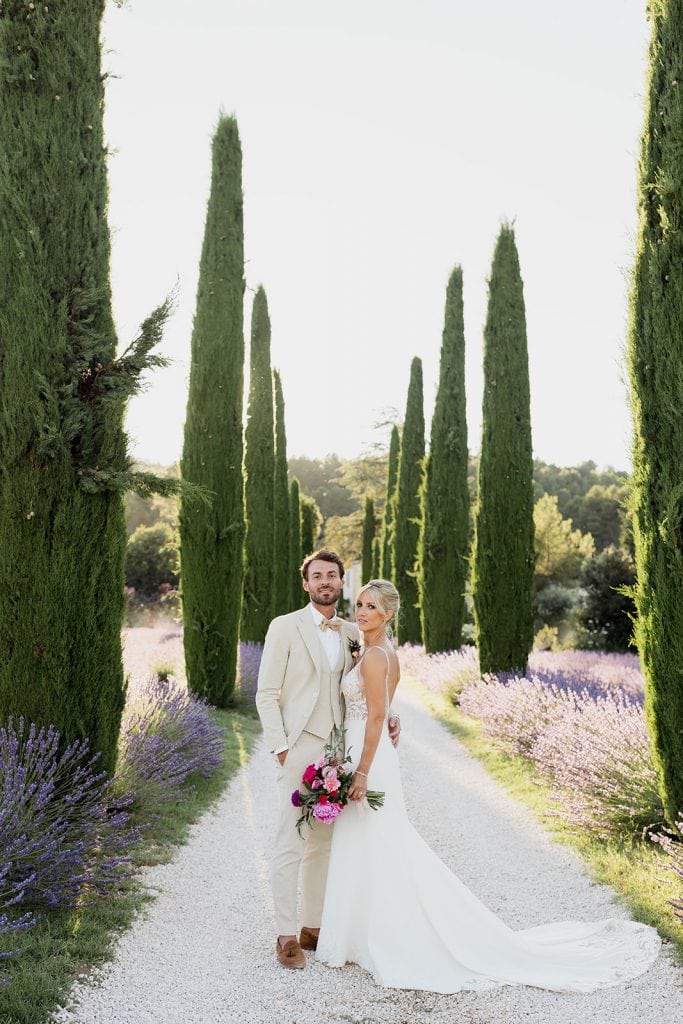 The bride and groom couple in the cypress and lavender aisle of Mas des Costes